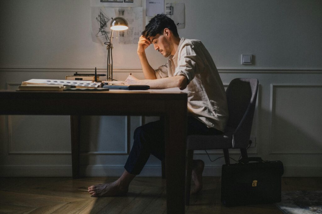 Emotional Burnout vs Quiet Satisfaction Concept Image Person sitting alone at night looking tired after long work session symbolizing obsession and burnout