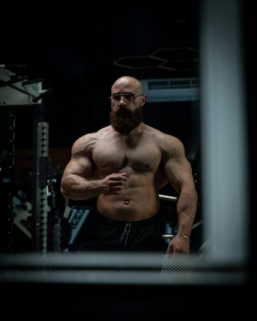 Man standing in front of a gym mirror reflecting on his fitness progress