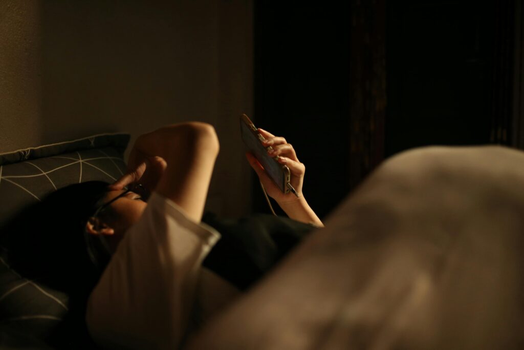 Person holding phone at night after sending a message, expressing mild anxiety and embarrassment