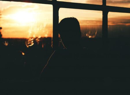 Man sitting alone by window at night reflecting on mental burnout affecting physical progress