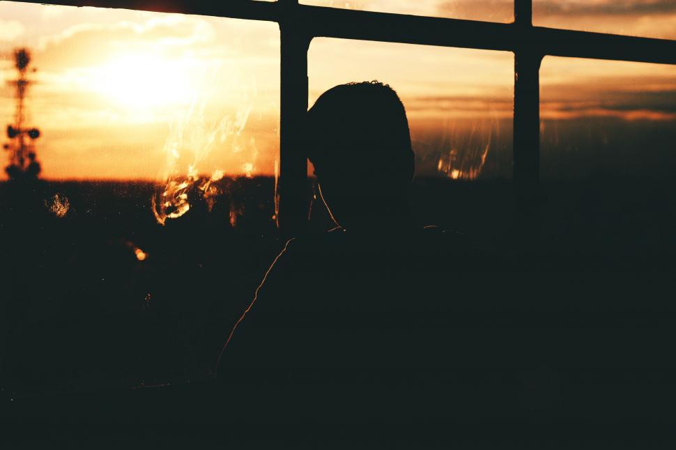 Man sitting alone by window at night reflecting on mental burnout affecting physical progress