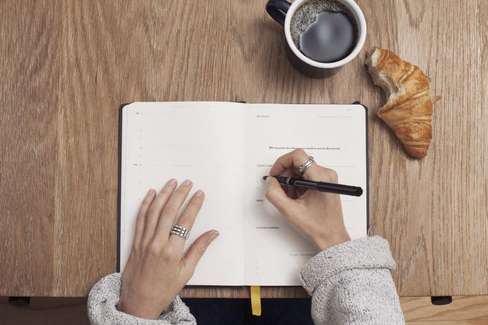 Workout plan written in notebook next to coffee in early morning light