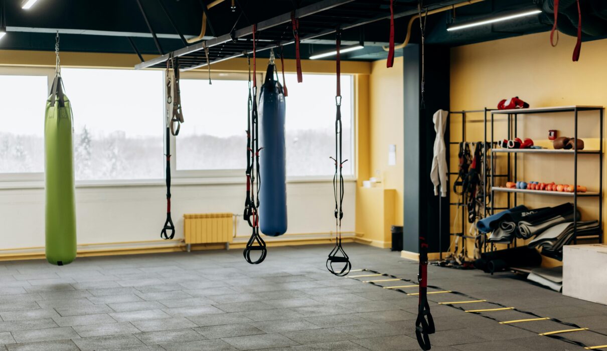 Empty gym in the early morning with soft natural light and a barbell set up on the floor