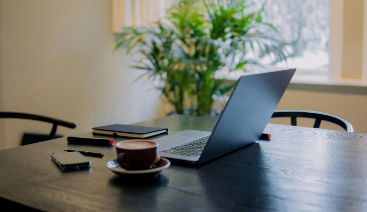 Person sitting alone at a desk in soft natural light, looking thoughtful and mentally fatigued.