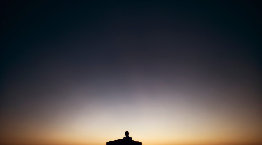 “Man sitting quietly at dawn reflecting before starting his day”