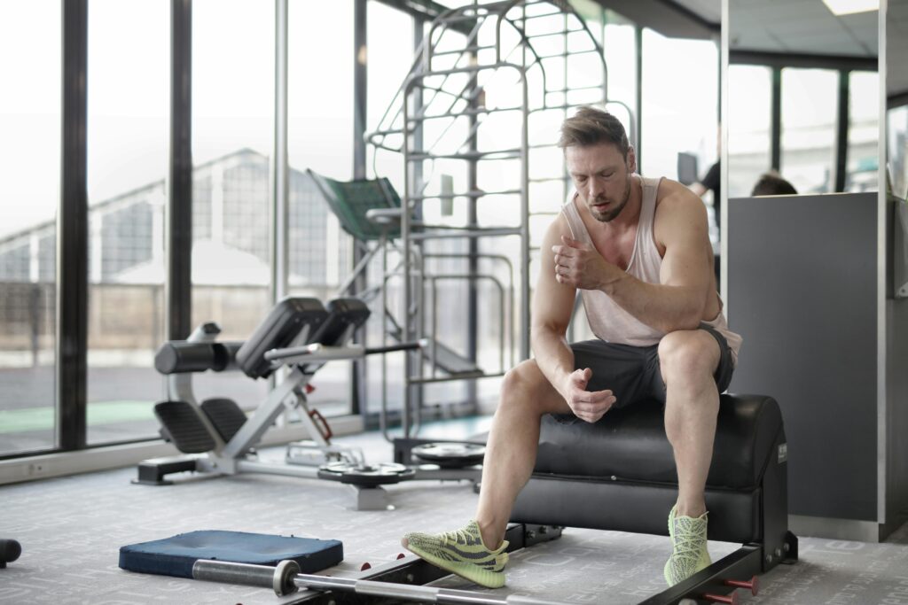 Gym member sitting on a bench between sets looking down thoughtfully