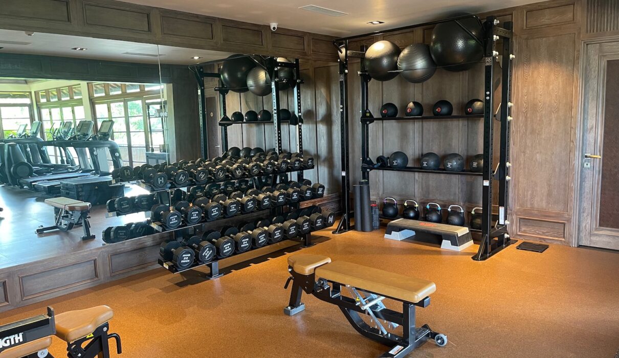Man sitting alone on gym bench after workout looking thoughtful about fitness consistency