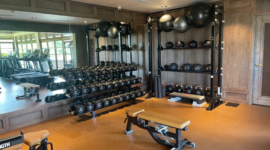 Man sitting alone on gym bench after workout looking thoughtful about fitness consistency