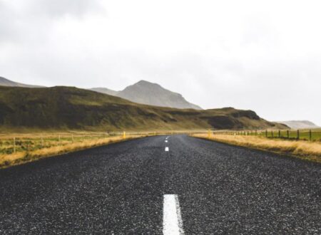 Empty road stretching into fog under a cloudy sky