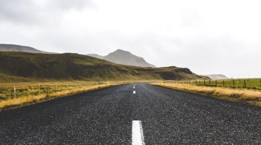 Empty road stretching into fog under a cloudy sky
