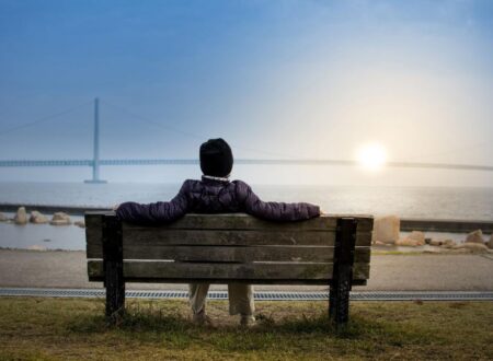 Person sitting quietly on park bench at sunrise reflecting on long-term lifestyle