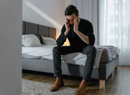 Person sitting on bed feeling mentally overwhelmed and exhausted