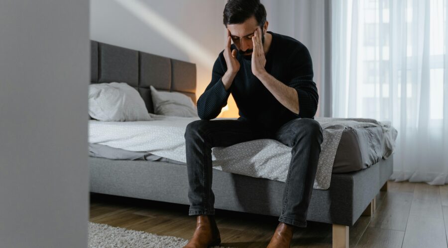 Person sitting on bed feeling mentally overwhelmed and exhausted