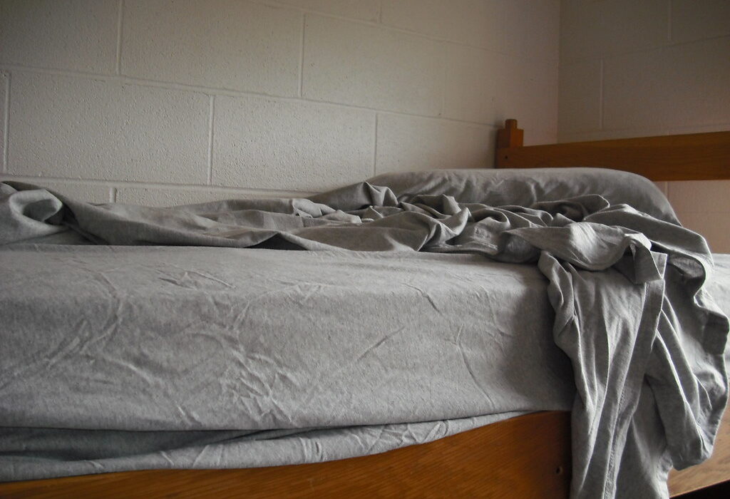 Unmade bed with early morning light symbolizing the struggle to get up for training