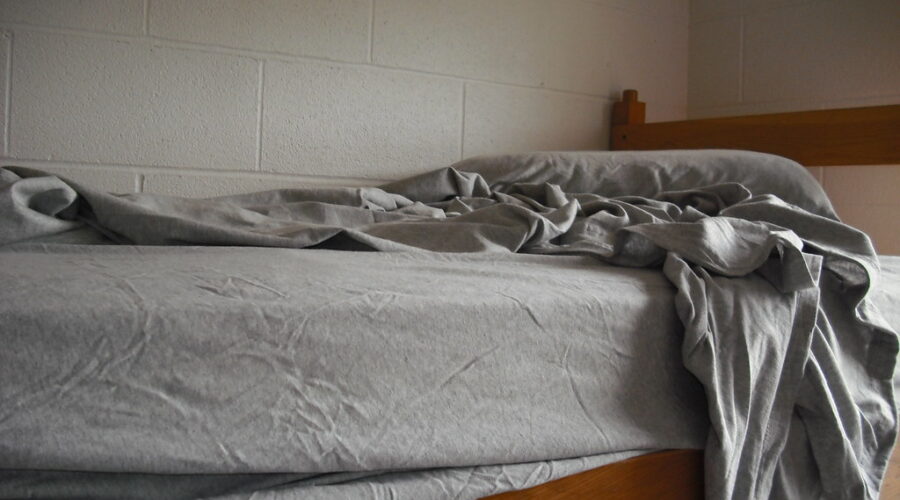 Unmade bed with early morning light symbolizing the struggle to get up for training