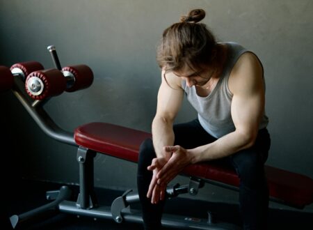 man sitting alone in gym looking tired and thoughtful about fitness consistency