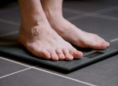 Person checking weight on scale during weight loss journey