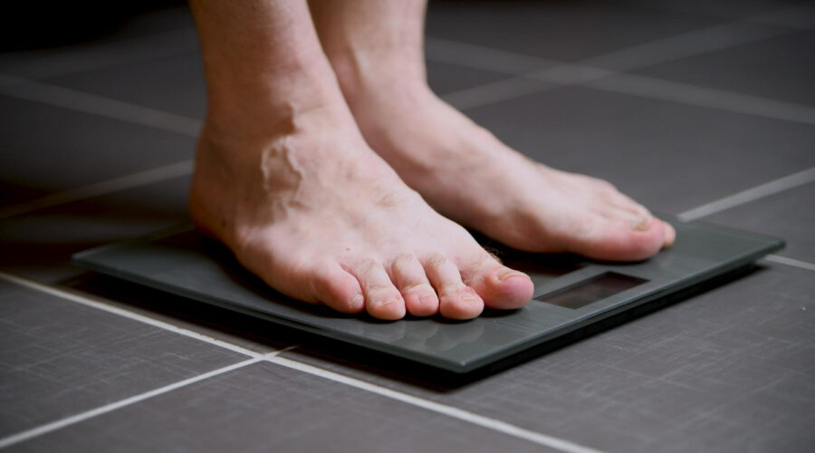 Person checking weight on scale during weight loss journey