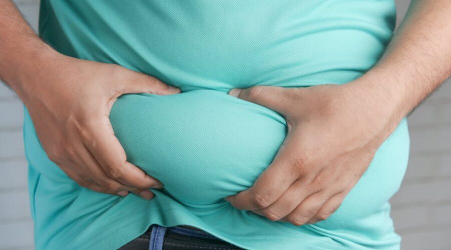 Person looking at their stomach in mirror realizing flat stomach comes from fat loss not ab exercises